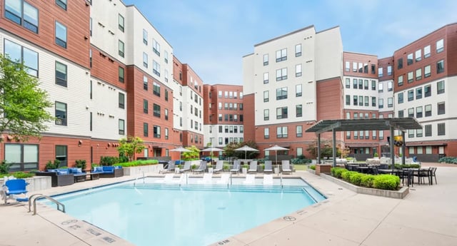 Swimming pool lounge chairs umbrellas outdoor seating area exterior at The Yard in Ann Arbor Student Accommodation