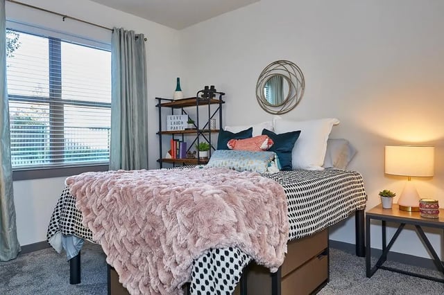 Bed with pink throw and bedside lamp bedroom at 848 Mitchell in Arlington Student Accommodation