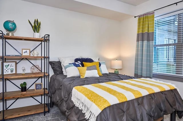 Bed with globe plant shelf and yellow striped throw bedroom at 848 Mitchell in Arlington Student Accommodation