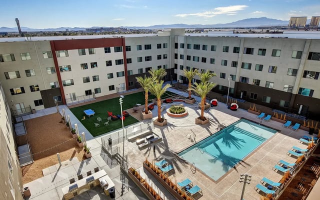 Courtyard with pool lounge chairs and palm trees exterior at Echo 1055 Apartments in Las Vegas Student Accommodation