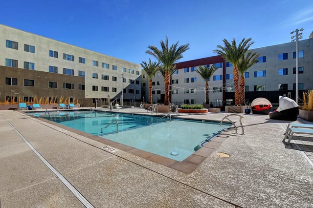 Pool lounge chairs palm trees student housing exterior at Echo 1055 Apartments in Las Vegas Student Accommodation