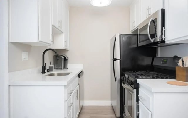 White cabinets sink and black stove refrigerator kitchen at USC Student Housing: Heritage 2353 in Los Angeles Student Accommodation