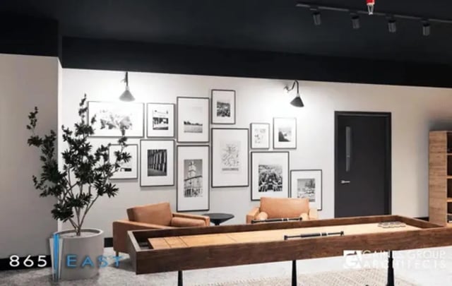 Shuffleboard table armchairs gallery wall and plant communal area at 865 East in Harrisonburg Student Accommodation