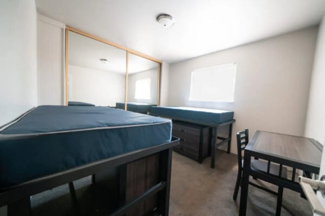 Two beds dresser table chairs mirrored closet bedroom at Centennial Apartments in Provo Student Accommodation