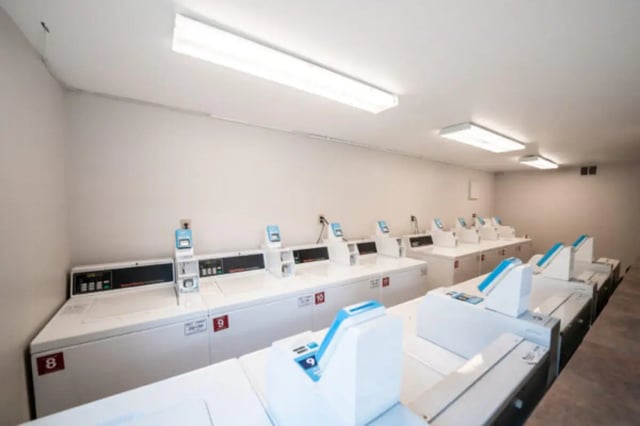 Row of white washing machines with blue and grey controls laundry room at Centennial Apartments in Provo Student Accommodation