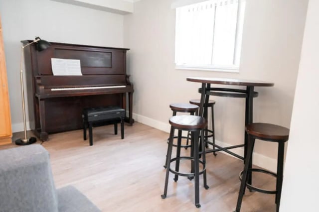 Piano with bench and high stools living room at Centennial Apartments in Provo Student Accommodation