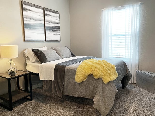 Bed pillows artwork nightstand and bright window bedroom at Eight Thirty Water Tower Apartments in Big Rapids Student Accommodation