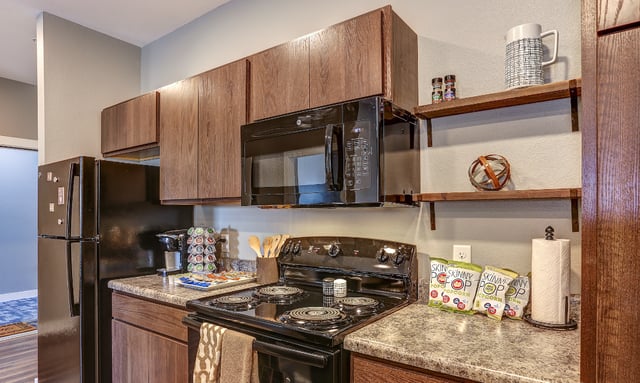 Black refrigerator microwave stove popcorn kitchen at Eight Thirty Water Tower Apartments in Big Rapids Student Accommodation