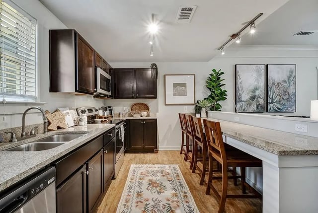 Dark wood cabinets granite counters and bar stools kitchen at Cottages at San Marcos in San Marcos Student Accommodation