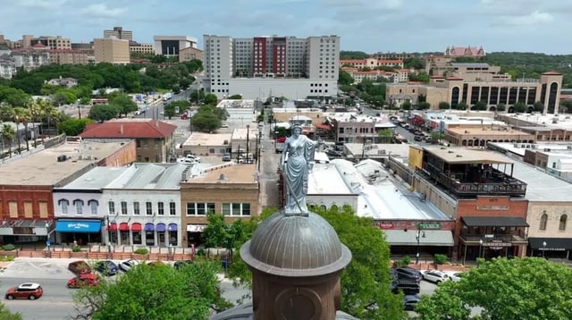 Statue atop dome overlooks city buildings exterior at Cottages at San Marcos in San Marcos Student Accommodation