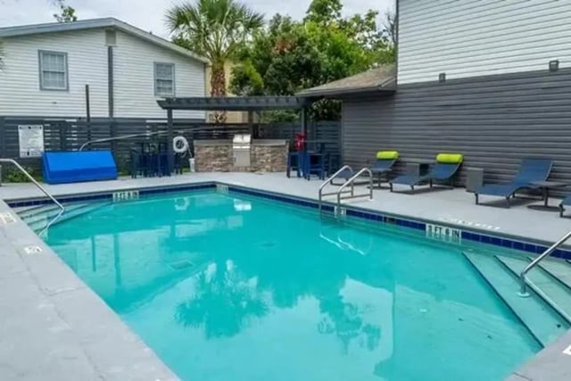 Pool with lounge chairs and outdoor kitchen area exterior at Campus Row in Tallahassee Student Accommodation