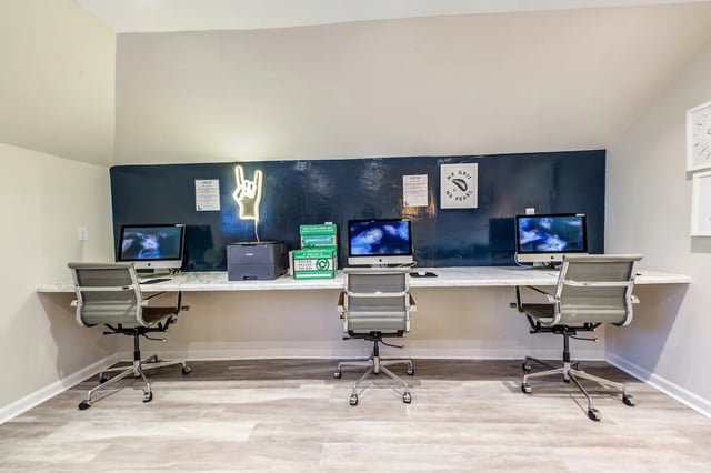 Computers printer chairs and neon sign study area at Campus Row in Tallahassee Student Accommodation