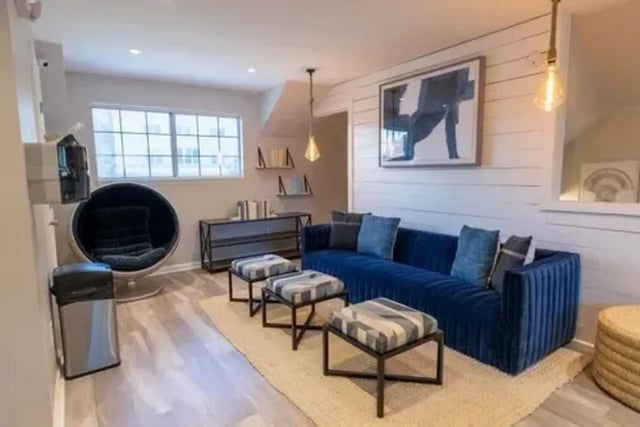 Blue sofa ottomans art bin chair living room at Campus Row in Tallahassee Student Accommodation