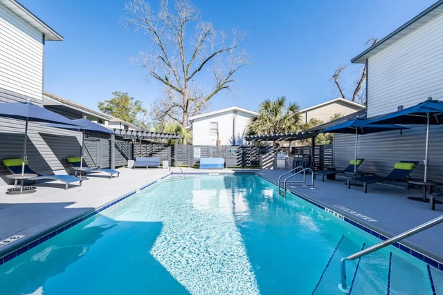 Pool with lounge chairs and umbrellas amenity area at Campus Row in Tallahassee Student Accommodation