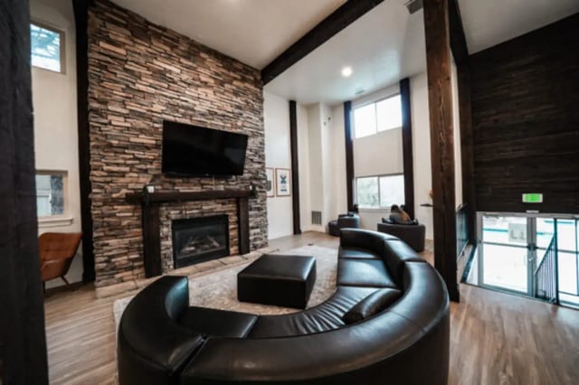 Curved sofa stone fireplace TV living area at Glenwood Apartments in Provo Student Accommodation