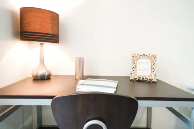 Desk with lamp books frame and chair study area at Apple Lane Apartments in Lawrence Student Accommodation