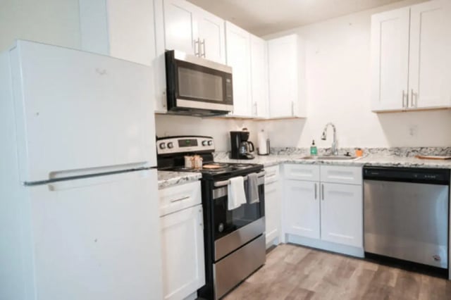 White refrigerator stove dishwasher white cabinets kitchen at Apple Lane Apartments in Lawrence Student Accommodation