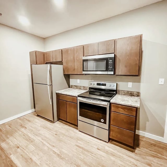 Stainless steel appliances and wood cabinets kitchen at Fireside District Apartments in Stephenville Student Accommodation