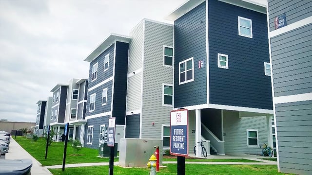 Modern apartment buildings with blue and grey siding exterior at Fireside District Apartments in Stephenville Student Accommodation