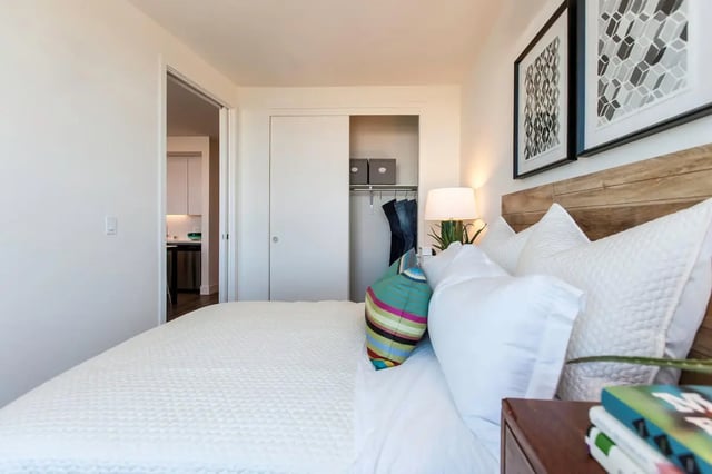 Bed with white bedding closet with clothes bedroom at The Dwight by Arthaus in Berkeley Student Accommodation