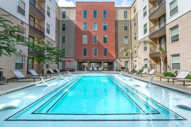 Resort pool with lounge chairs exterior at Campus Vue Apartments in Houston Student Accommodation
