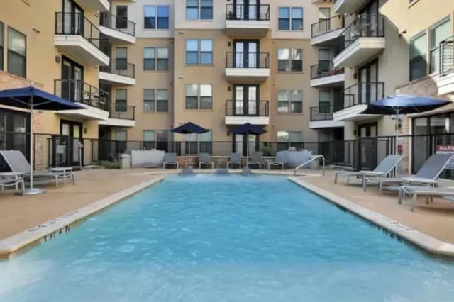 Apartment building pool with lounge chairs and umbrellas exterior at GrandMarc Austin in Austin Student Accommodation