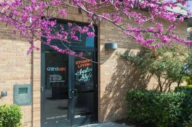 Building entrance with flowering tree exterior at GrandMarc Austin in Austin Student Accommodation