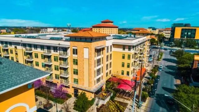 Yellow apartment building with balconies and street exterior at GrandMarc Austin in Austin Student Accommodation