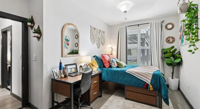 Bed desk chair mirror plants bedroom at The Local Downtown in San Marcos Student Accommodation