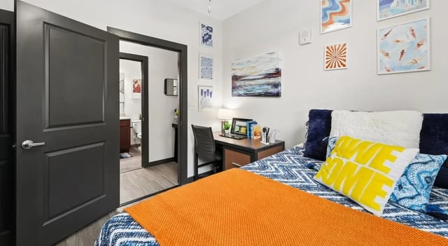 Bed desk and door in student bedroom at The Local Downtown in San Marcos Student Accommodation