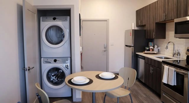 Stacked washer dryer round table with place settings kitchen at Legacy202 Apartments in Champaign Student Accommodation