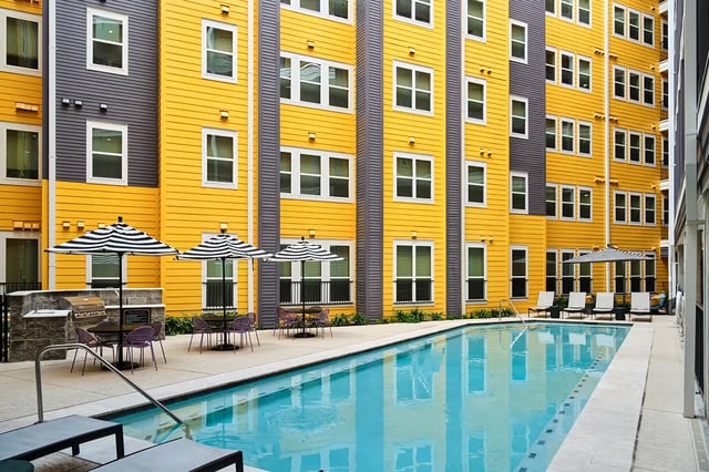 Umbrella tables chairs grill pool and lounge chairs exterior at Flatiron in Baton Rouge Student Accommodation