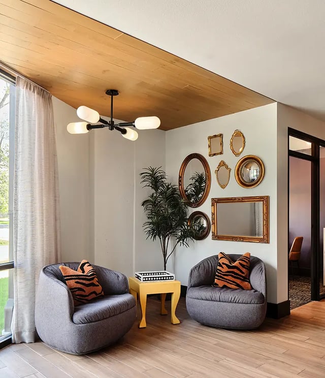 Two chairs plant table mirrors living room at Flatiron in Baton Rouge Student Accommodation