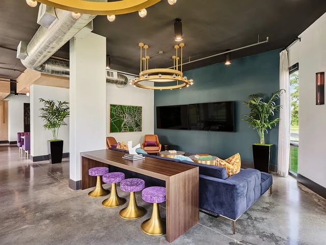 Sofa stools plants and TVs living room at Flatiron in Baton Rouge Student Accommodation