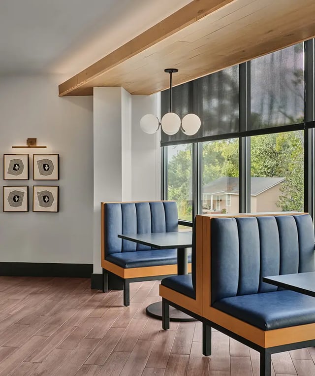 Blue booths and tables by large window common area at Flatiron in Baton Rouge Student Accommodation