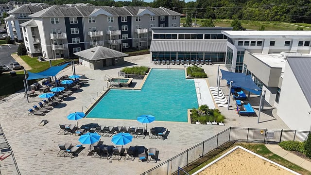 Pool lounge chairs umbrellas complex exterior at Magnolia, A Prosper Community in Tuscaloosa Student Accommodation
