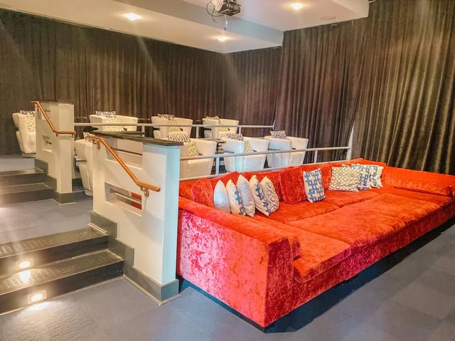 Large red sofa tiered white seats cinema room at Magnolia, A Prosper Community in Tuscaloosa Student Accommodation