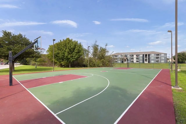 Basketball court with hoops and apartment buildings exterior at Mirage San Marcos in San Marcos Student Accommodation