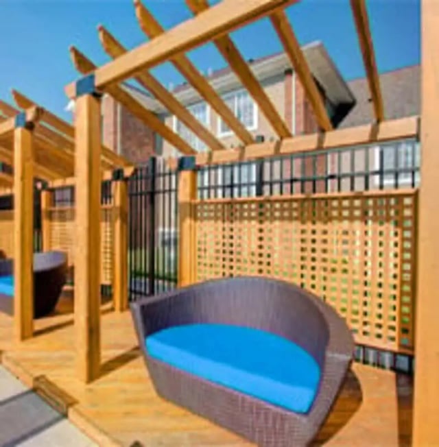 Wicker couches with blue cushions under pergola outdoor seating area at Knollwood Apartments in Kalamazoo Student Accommodation