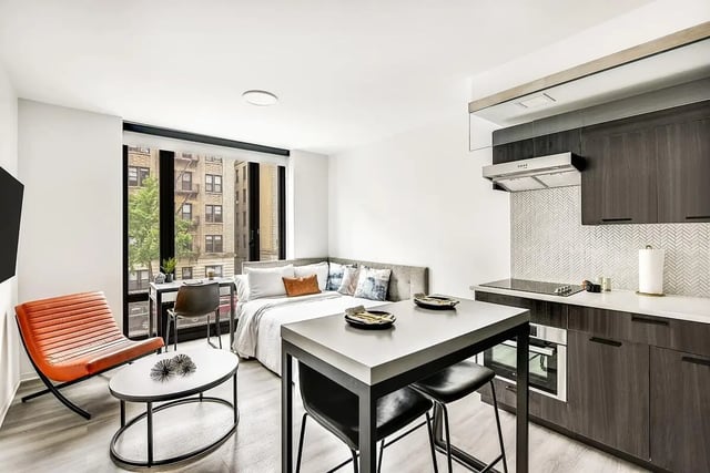 Modern studio apartment with bed, kitchen, and desk. at Monarch Heights Apartments