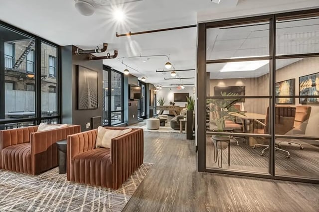 Two plush chairs large windows and modern decor living area at Monarch Heights Apartments