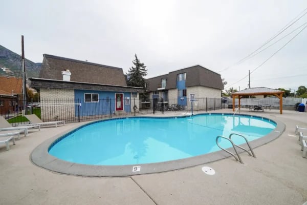 Blue swimming pool with lounge chairs and gazebo Exterior at Monticello Apartments in Provo Student Accommodation
