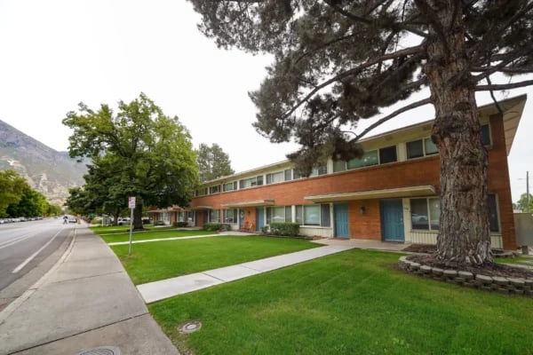 Brick apartment building with blue doors and green lawn exterior at Monticello Apartments in Provo Student Accommodation