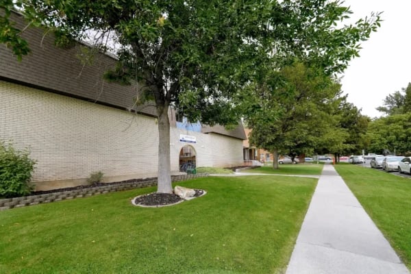 Brick building with trees and sidewalk exterior at Monticello Apartments in Provo Student Accommodation