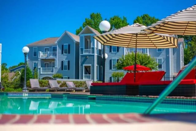 Pool lounge chairs umbrellas apartments exterior at Pointe At Troy in Troy Student Accommodation