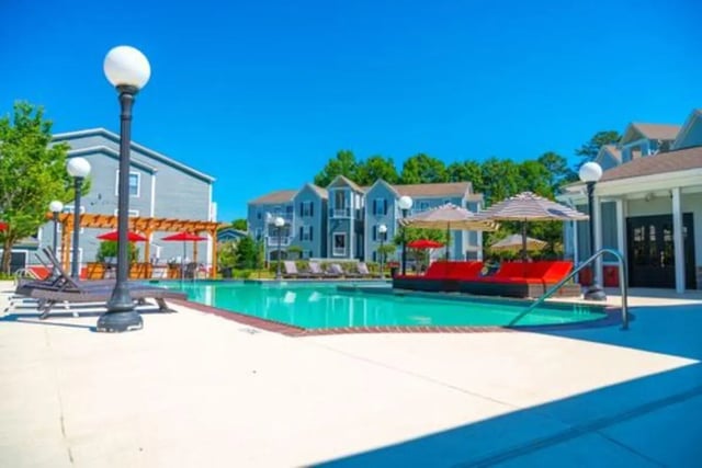 Pool lounge chairs umbrellas buildings exterior at Pointe At Troy in Troy Student Accommodation