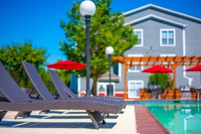 Lounge chairs by pool with umbrellas exterior at Pointe At Troy in Troy Student Accommodation