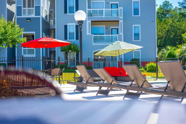 Lounge chairs red and striped umbrellas exterior at Pointe At Troy in Troy Student Accommodation