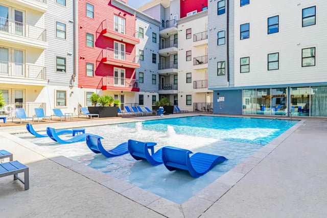 Blue lounge chairs in shallow pool exterior at Pointe San Marcos in San Marcos Student Accommodation