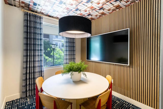 Round table plant four chairs and television communal area at Pointe San Marcos in San Marcos Student Accommodation